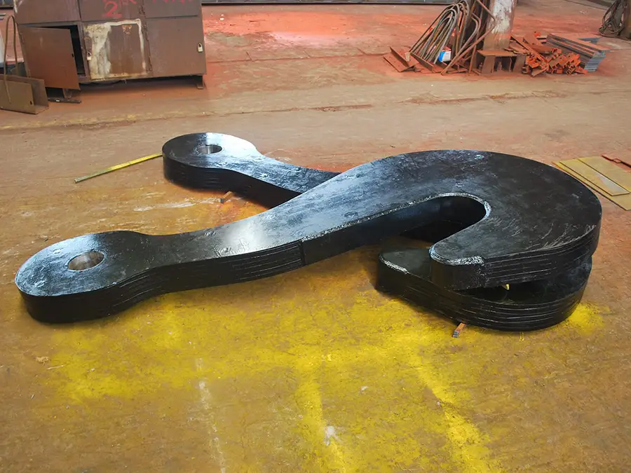 Laminated crane hook lying flat on the workshop floor, front angle