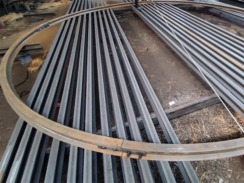 Steel rails bent to specified radius for curved track sections in tunnels or industrial rail systems.