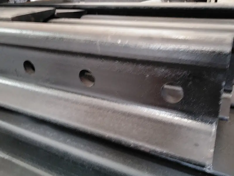 Steel rails with custom-drilled holes for fishplates during track installation.