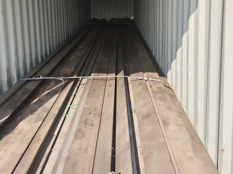 Heavy rail sections secured with steel straps to maintain bundle stability during handling and transportation.